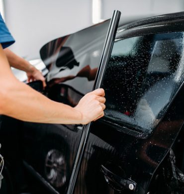 Male specialist applying car tinting film Male specialist applying car tinting film, installation process, tinted auto glass installing procedure